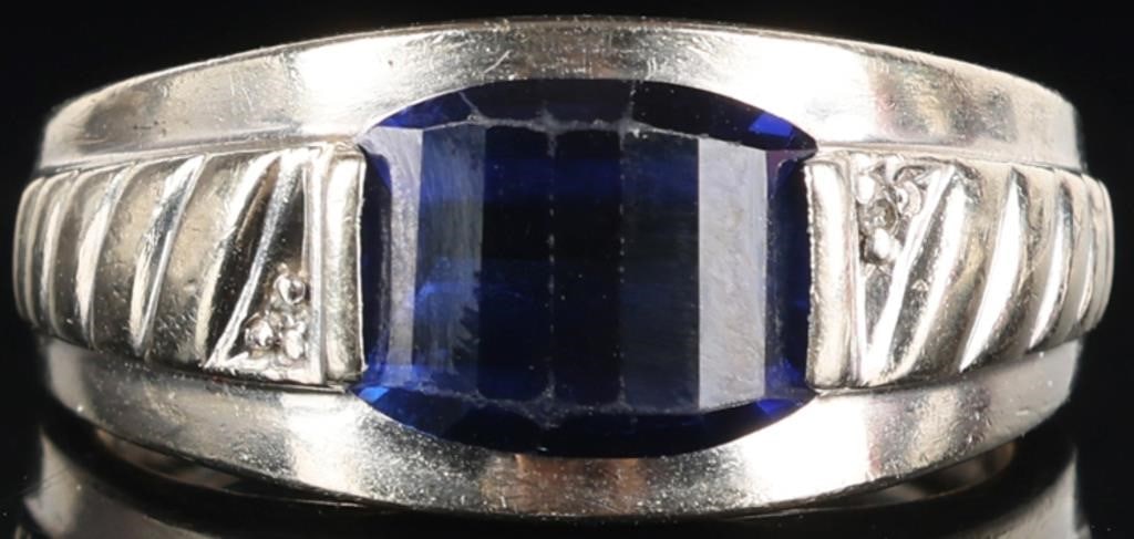10K WHITE GOLD MENS RING W/ SAPPHIRE & DIAMONDS: 10k white gold mens ring with a 10 x 8.3 mm fancy cut blue sapphire center gemstone with a melee diamond set on either side of it. The shoulders are decorated with Art Deco motifs. Stone Type: Diamond