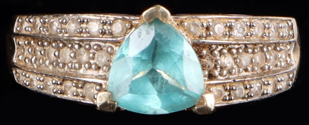 10K YELLOW GOLD LADIES RING W/ TOURMALINE & DIAS: 10k yellow gold ladies ring with a 1ct trillion-cut light blue tourmaline center gemstone flanked by thirty-two accessory melee diamonds on the shoulders (sixteen on either side) and four melee diamon