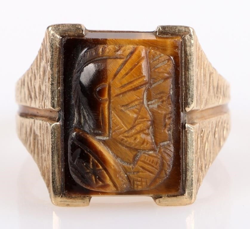 10K YELLOW GOLD CARVED TIGERS EYE MEN'S RING: 10K yellow gold carved tigers eye men's ring to include one 15.68 X 11.95 mm carved tigers eye. The carving depicts two roman soldiers. Stone Type: Tigers Eye Weight: 8.79 Grams Size: 8.25 U.S. Condit