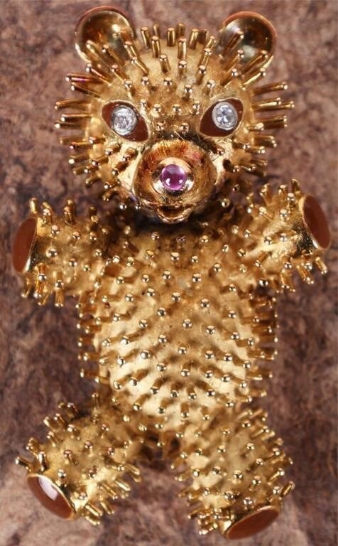 18K YELLOW GOLD TEDDY BEAR PENDANT W/ DIAS & RUBY: 18K yellow gold teddy bear pendant. The surface is covered in filaments designed to make the bear appear fuzzy. The paws are colored with brown enamel. The eyes are two 0.05ct round-cut diamonds and t