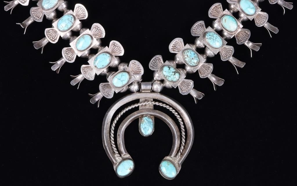 SOUTHWEST STYLE 925 SQUASH BLOSSOM NECKLACE W TURQ: Southwest style sterling silver ladies necklace with squash blossom patterns along its length and a horseshoe as its pendant. The piece features turquoise stones throughout. Stone Type: Turquoise Weig