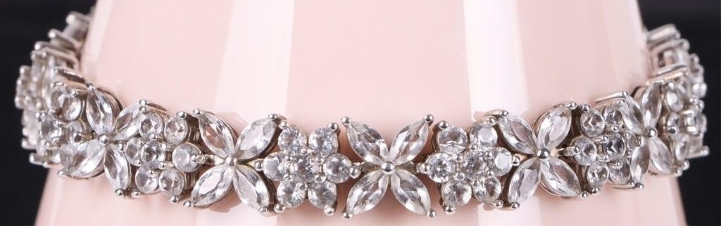 STERLING SILVER WHITE TOPAZ FLOWER MOTIF BRACELET: Delicate elegance meets timeless sparkle in this beautifully crafted sterling silver bracelet. Designed with an enchanting floral motif, each flower is adorned with shimmering white topaz stones that 