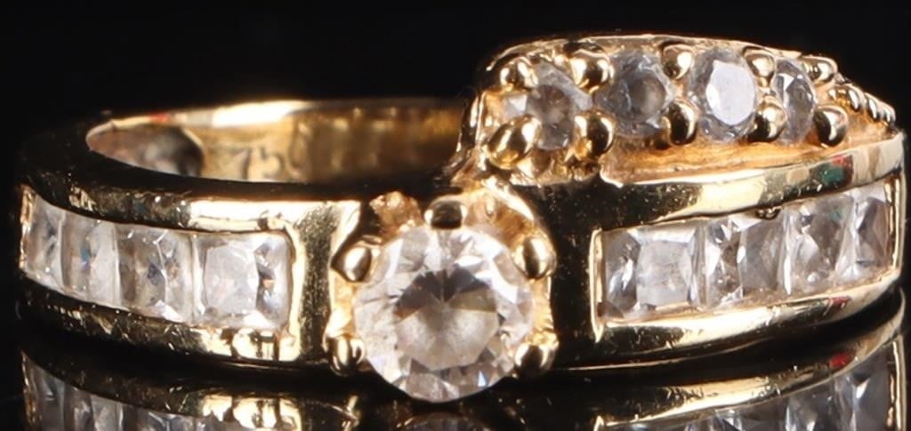 18K YELLOW GOLD LADIES RING W/ CUBIC ZIRCONIUM: 18K yellow gold ladies ring with a round-cut cubic zirconium center stone, square-cut cubic zirconia stones flanking it, and a row of three small round-cut stones on a ribbon molded beneath the band. 