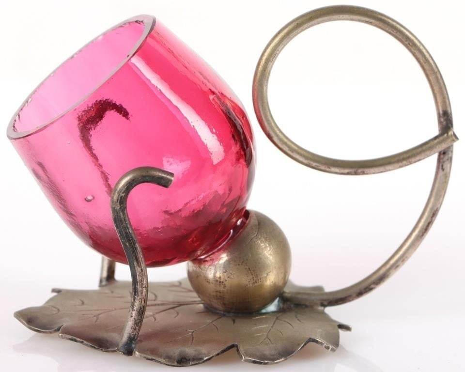 ANTIQUE SILVER-PLATED CRANBERRY GLASS HOLDER: Antique silver-plated cranberry glass holder. The holder itself has a base in the shape of a leaf and the glass is removable. Size: 3.5" X 2.25" X 2" Condition: See pictures