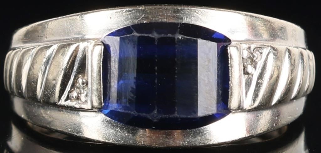 10K WHITE GOLD MENS RING W/ SAPPHIRE & DIAMONDS: 10k white gold mens ring with a 10 x 8.3 mm fancy cut blue sapphire center gemstone with a melee diamond set on either side of it. The shoulders are decorated with Art Deco motifs. Stone Type: Diamond