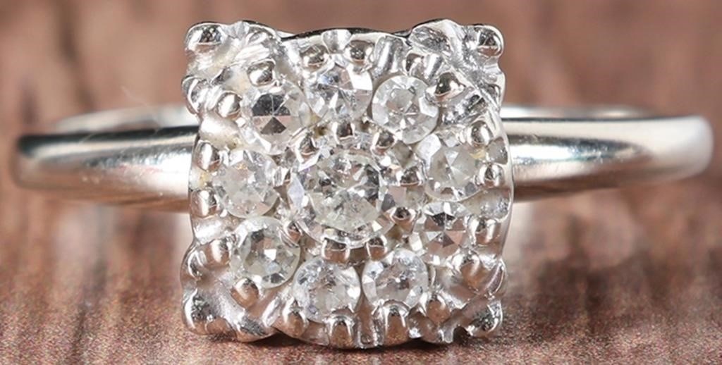 LARGE 14K WHITE GOLD LADIES RING W/ DIAMOND: Large 14k white gold ladies ring with a square crown encrusted with a 0.2ct round-cut center diamond surrounded by nine 0.04ct round-cut accessory diamonds. Stone Type: Diamond Weight: 4.33 grams Size
