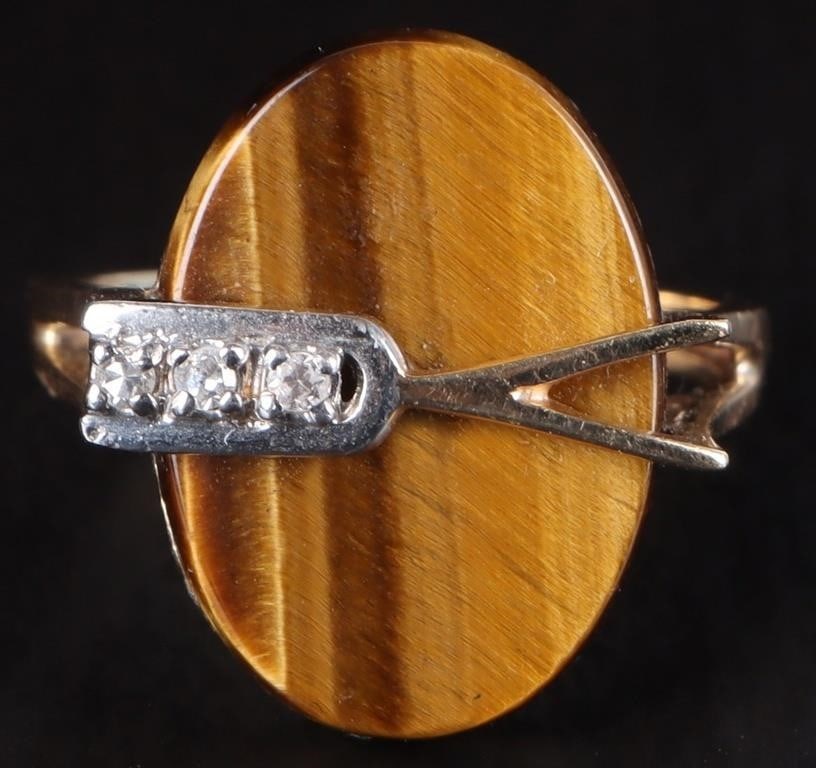 10K YELLOW GOLD LADIES RING W/ TIGERS EYE & DIAS: 10k yellow gold ladies ring with a large flat tigers eye oval. A gold band bisects its surface and its left side is occupied by three small diamonds - the area behind them is white gold. Stone Type: D