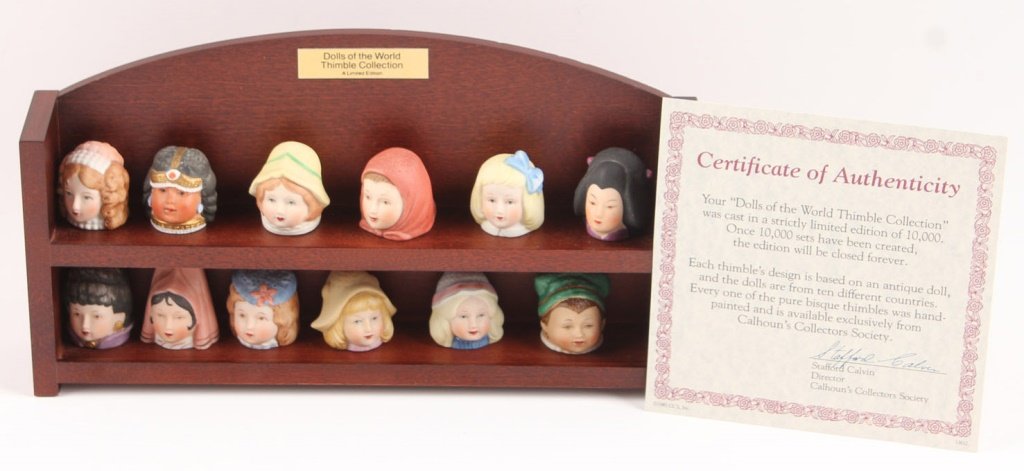 CALHOUNS DOLLS OF THE WORLD THIMBLE COLLECTION: CALHOUNS DOLLS OF THE WORLD THIMBLE COLLECTION The 1981 "Dolls of the World" porcelain 12 thimble collection by the Franklin Mint. Includes wooden stand, COA, and individual informational pamphlets. S