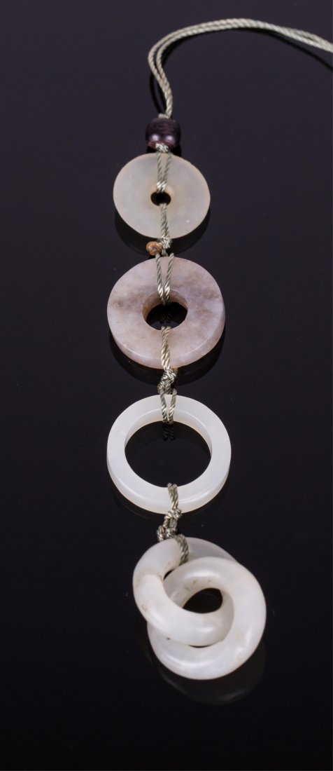 CHINESE WHITE JADE RINGS ORNAMENT: Qing dynasty, four jade disk ring tied up on a string as an ornament; 5/8 in. w