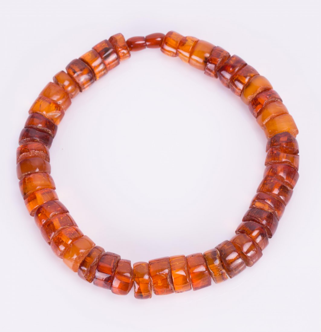 AN AMBER NECKLACE: early 20th century; necklace (16 1/2 in. l), bead (3/4 in. diameter)