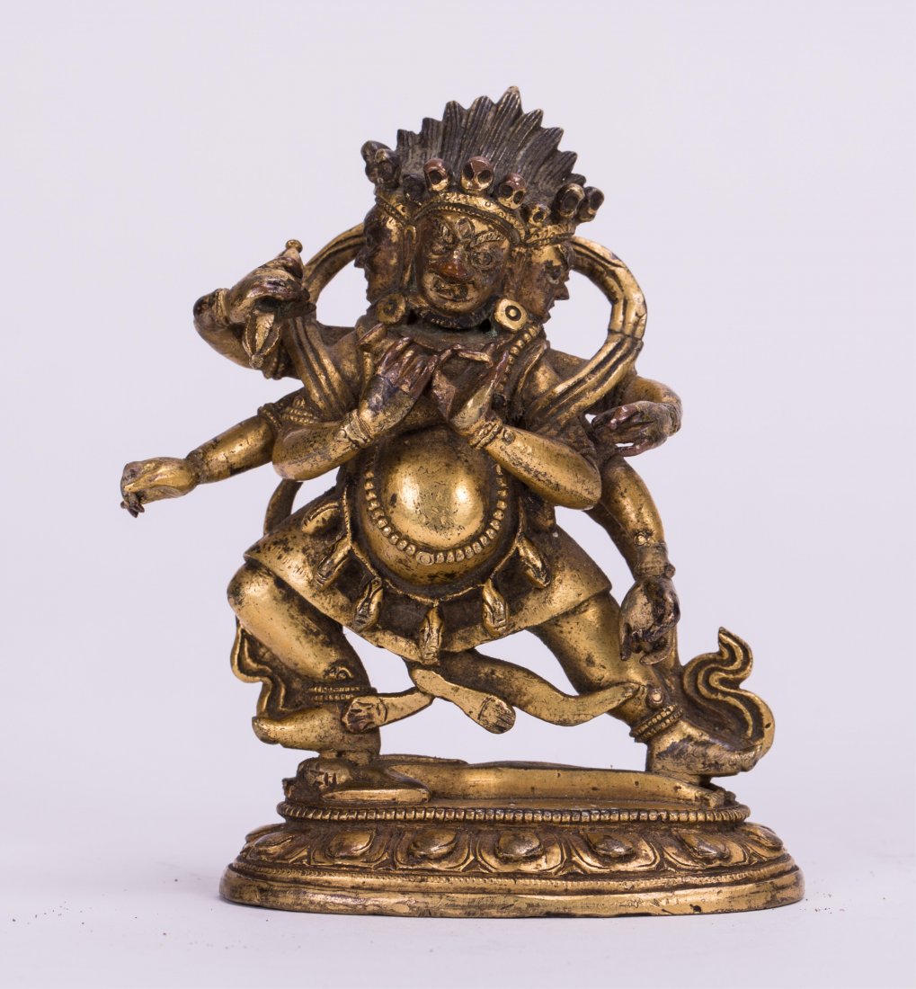 SINO TIBETAN GILT BRONZE GUARDIAN: 17th / 18th century, multiple arms with attributes standing on lotus base; 3 1/2 in. h, 2 3/4 in. w