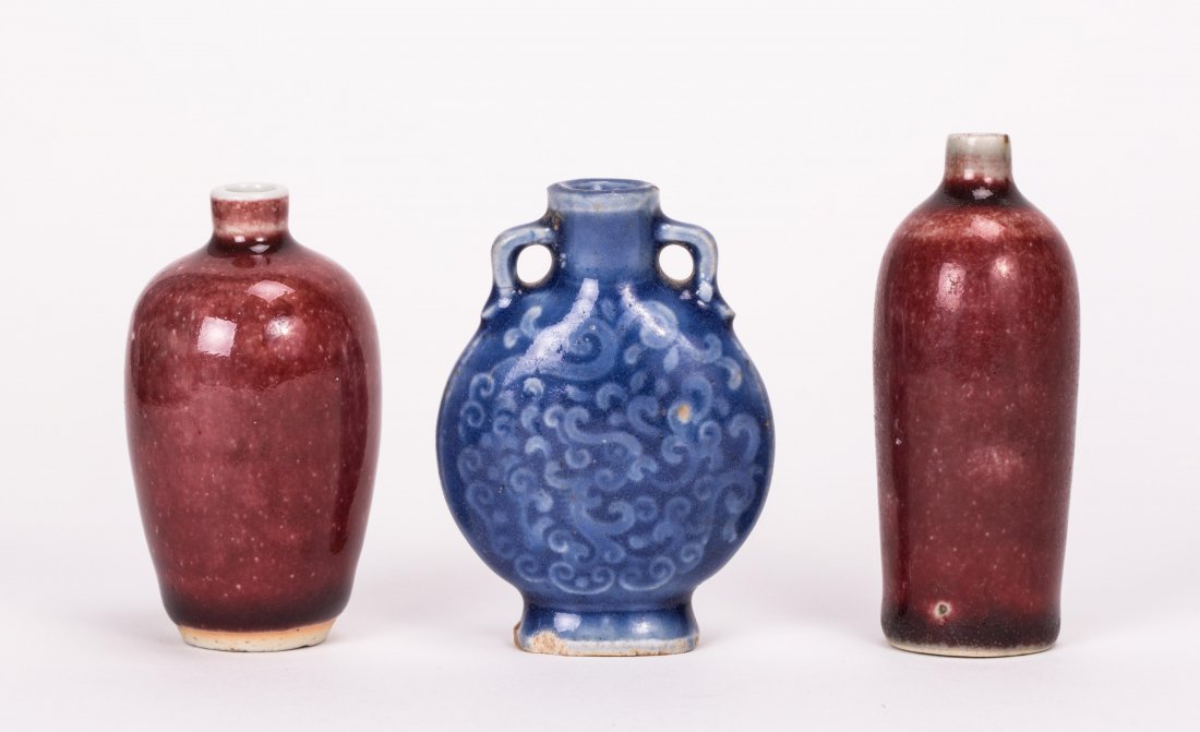THREE CHINESE PORCELAIN SNUFF BOTTLES: 19th century; two oxblood, one molded blue; tallest (3 1/4 in. h), widest (2 in. w)