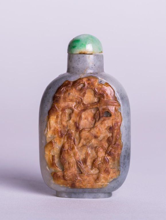 CHINESE JADE CARVED SNUFF BOTTLE WITH RUSSET: Qing dynasty; gray and white jade snuff bottle with front side, a large area of skin carved figures in mountain scene in high relief, back side has a flower tree motif; jadeite stopper; 3 in. h