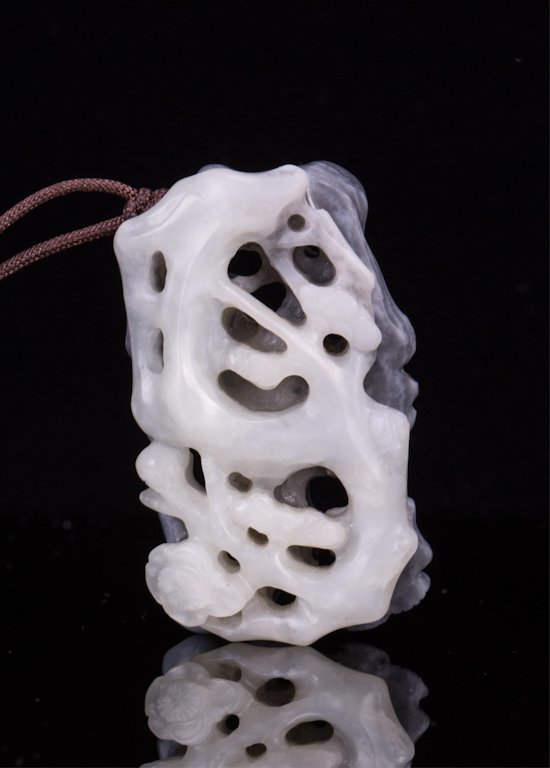 CHINESE TWO TONE BLACK AND WHITE JADE PENDANT: 19th century, plum blossom motif; 2 1/8 in. h, 1 1/4 in. w