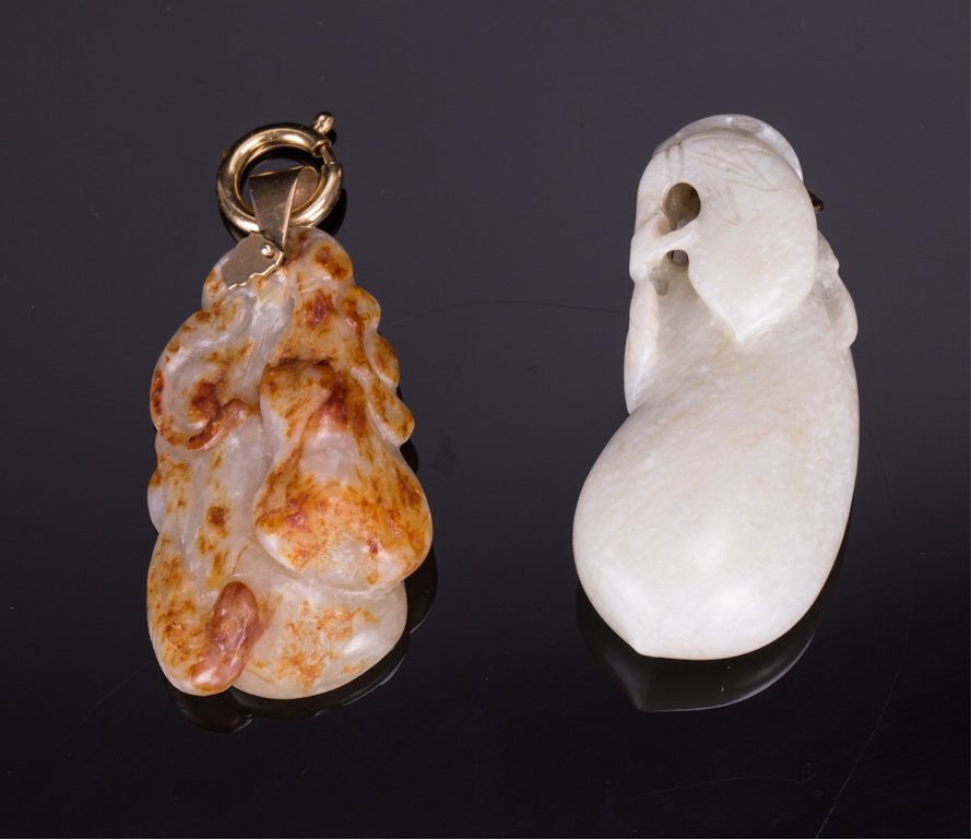 TWO CHINESE JADE PENDANTS: 19th century; one with skin, another in shape of eggplant; 2 in. h