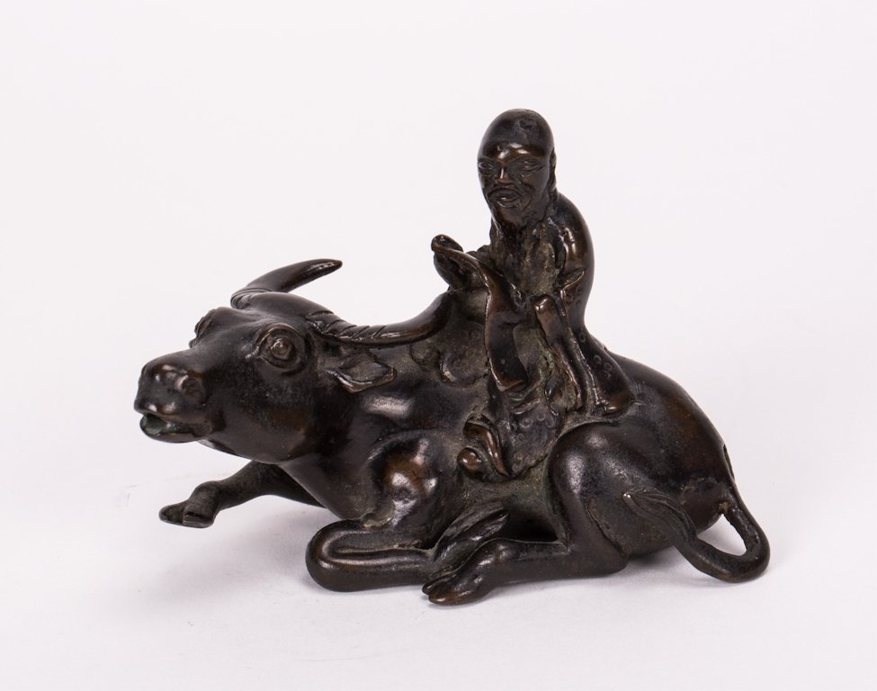 CHINESE BRONZE PAPER WEIGHT OF SCHOLAR RIDING OX: 18th / 19th century; 3 in. h, 4 1/4 in. w