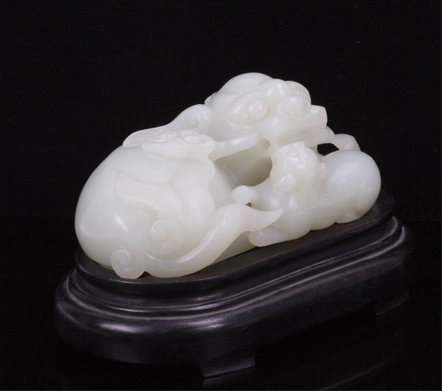 CHINESE CELADON JADE FOO LION WITH WOODEN BASE: 20th century; 4 by 2 1/4 in., 2 3/4 in. h