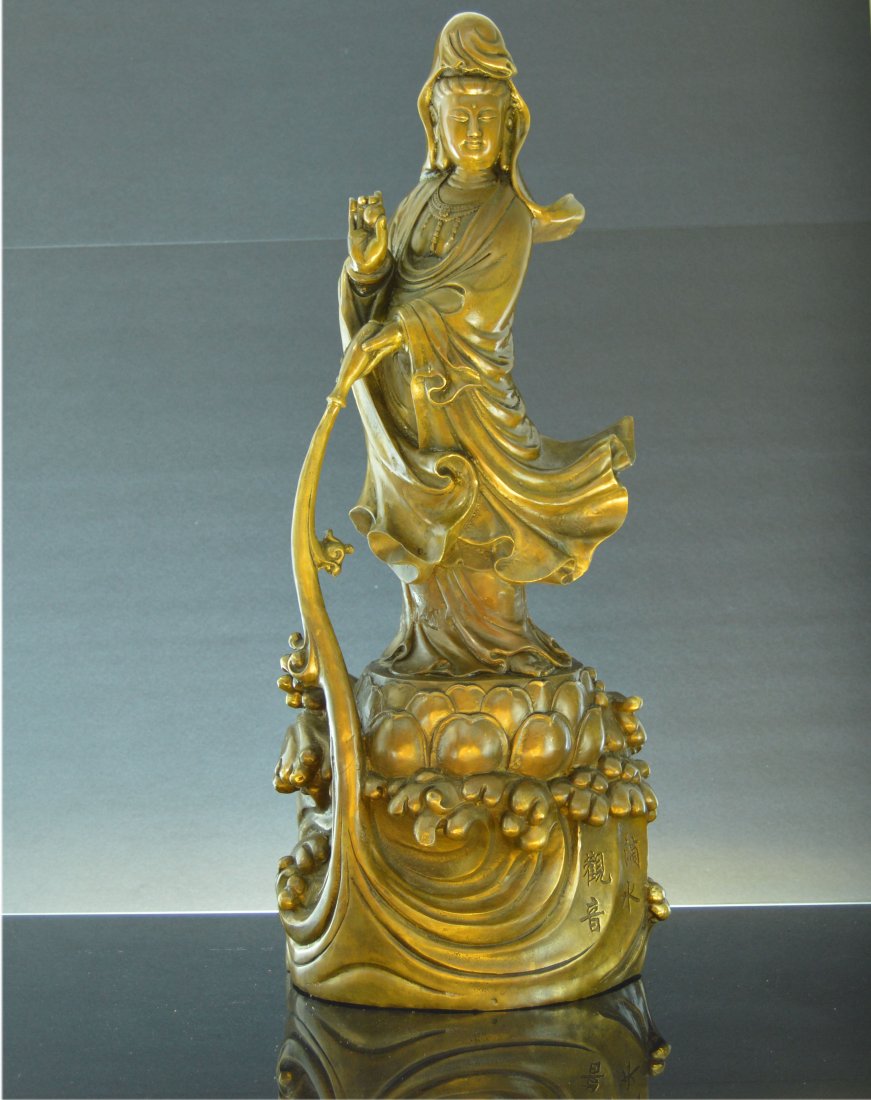 Antique Chinese Gilt Bronze GuanYin Statue: A Beautiful Chinese gilt bronze figure of GuanYin in flowing robes with a small headdress standing upon the waves and pouring her bottle of tears into the sea. Engraved with chinese characters on the 