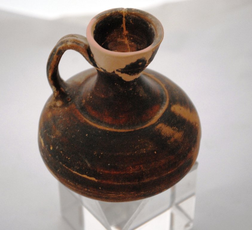 Greek Squat Lekythos Terracotta Vessel: Magna Graecia, Apulian, Ca. 4th century BCE.A beautifully formed squat vessel slipped in a black lead glaze. Vessel is composed of a low platform supporting a bulbous body, with high spout and connect