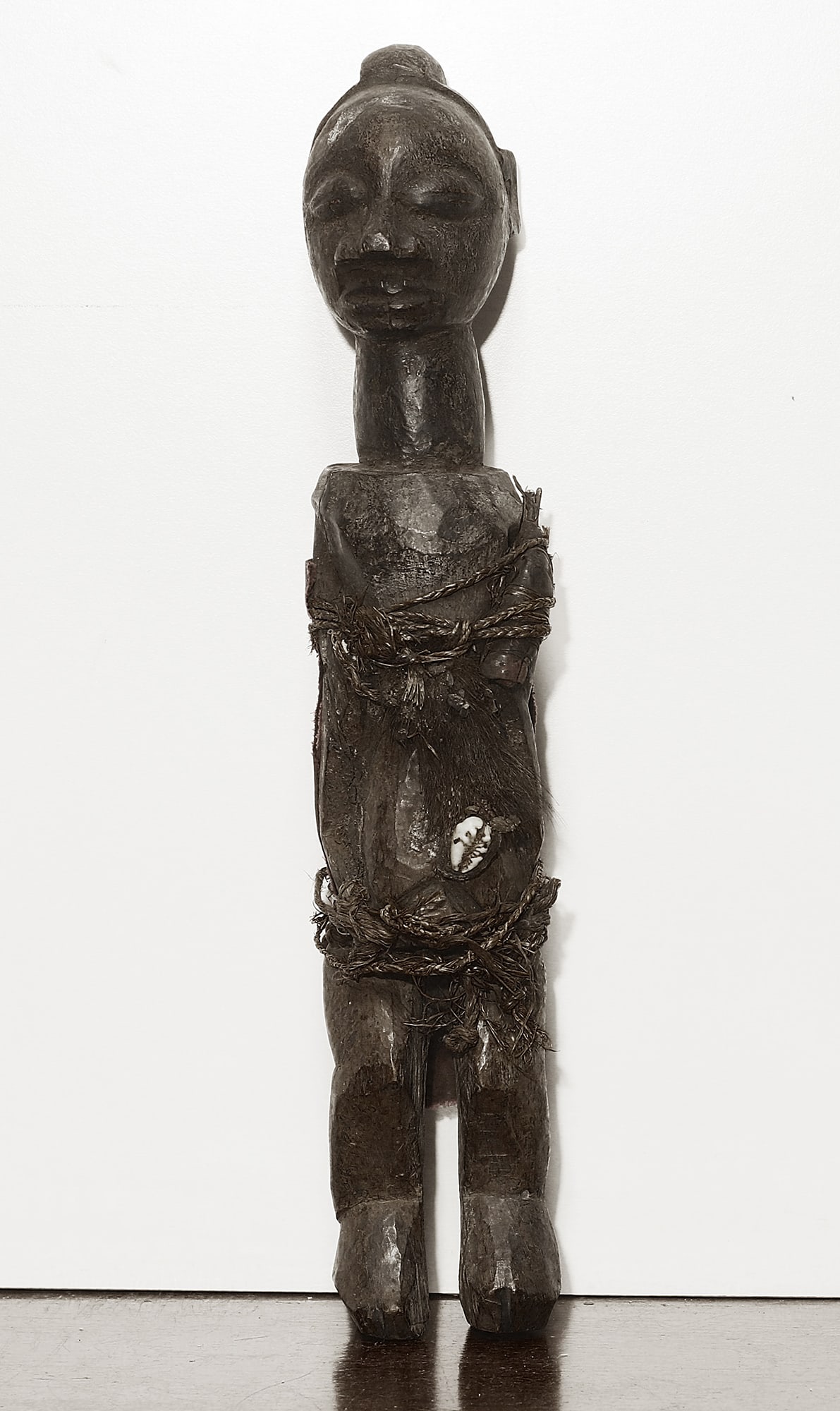 Congo Bayaka Handcarved wooden Fetish figure 40cm: Congo. 1970 circa. Bayaka people. Handcarved wooden Fetish figure decorated with shell, leather and cord. 704 gr. - 40x7x9 cm. Rare