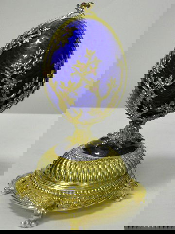 Faberge Sterling Silver & Enamel Musical Egg: Faberge musical egg. The marked 925 Silver gilt body of the egg is decorated with blue guillouche enamel and applied gem set branches opening to reveal a red velvet lined interior with a mythical bird