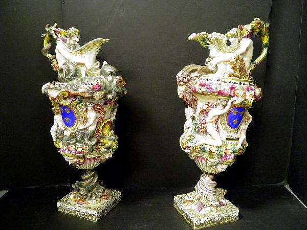 Pair of Large NFigural aples Covered Ewers: One representing the water with Poseidon supporting the handle with seashells, mermaids and dolphins applied to body. The other representing the earth with a Satyr supporting the handle and the body a