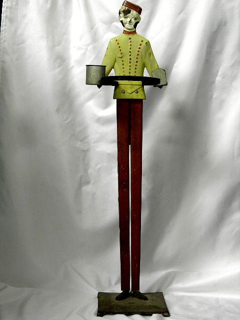 1930's Iron Bell Hop Umbrella Stick Stand: A fun 1930's iron polychrome umbrella/stick stand. Modelled as a bell hop wearing a yellow jacket, red buttons, pants and cap. Back stamped Patt applied for. He has a hoop to hold a stick or umbrella,