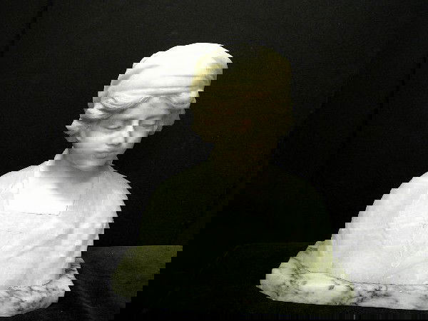 Alabaster Bust of A Woman On Marble Base: Antique finely detailed Alabaster bust of a young woman wearing a scarf and hair showing in front. Mounted on a black veined white marble base. Measures 11" high 10 1/2" wide and 5" deep. Note: glued