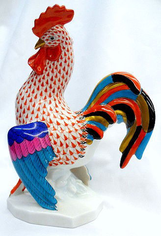Herend Hand Painted Porcelain Rooster Figure: Herend hand painted porcelain Rooster. This Rooster is colored in a rust and white fishnet design. The Rooster has a black, blue, rust and yellow feathered tail accented with purple, pink and blue and