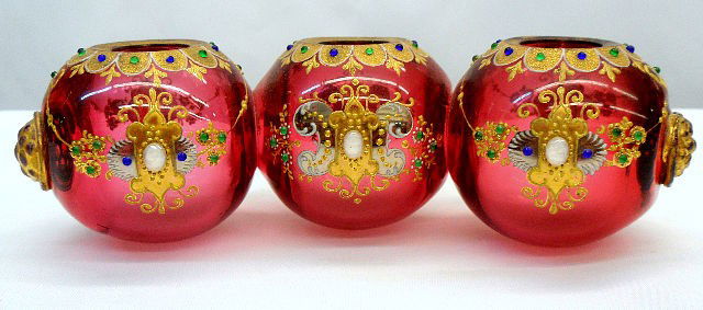 Moser Three Light Candle Holders: Moser three light hand painted cranberry colored glass. The Candle Holders are outlined with enamel & gilt work throughout. Holders have Beaded decoration with cluster of beads on each end. 2 1/4" hei