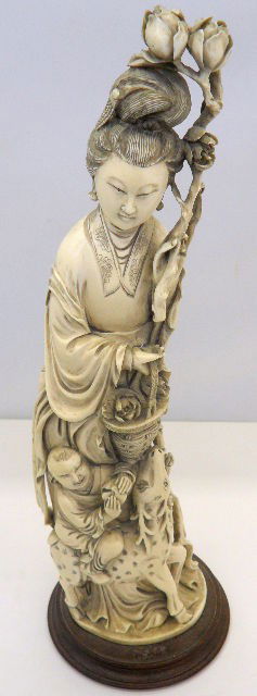 Chinese Carved Ivory Figural Group On Stand: Finely Carved Ivory Figure Of Kuan Yin On Wood Stand. Chinese Lady With Flowers In Her Hair, Holding Basket With Child And Reindeer Below. Measures 15 3/4" High x 3 3/4" Long. Shipping And Required In
