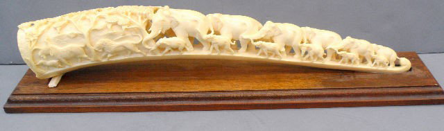 Chinese Carved Ivory Elephant Figural Tusk: Intricately carved ivory group of elephants looped together to form a bridge that seems to lead into a group of trees. Both big and little elephants figures are together. This figural elephant tusk si