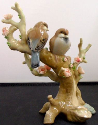 Lladro Bird Duet Figurine: Fabulous hand-made porcelain figurine of two birds in a tree. This piece represents two courting birds on a perch that features lovely pink flowers on all sides and branches. Hand-made in Valencia, Sp