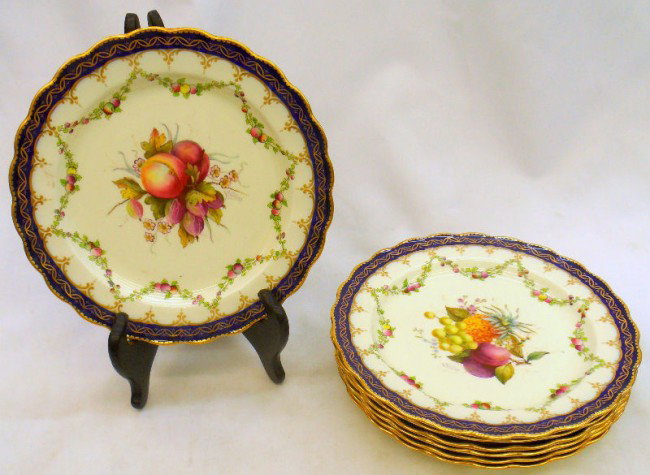 (12) Royal Worcester Handpainted Porcelain Plates: Set of 12 Royal Worcester hand painted porcelain salad plates. Cobalt blue band with gilt trimming and scalloped edge border. Center of plate depicts different fruits with leaves. Has a wreath design 