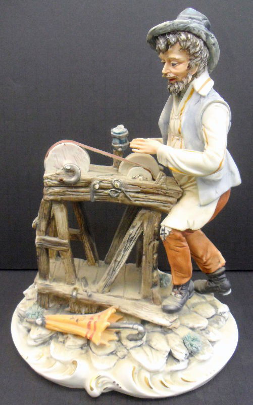 Capodimonte Figure of a Man: Italian handpainted Capodimonte figure of a man at a work bench sharpening tools. There is beautiful color and fine design to this piece. Do not miss out! Marked "N" stamp on base for Capodimonte. Mea