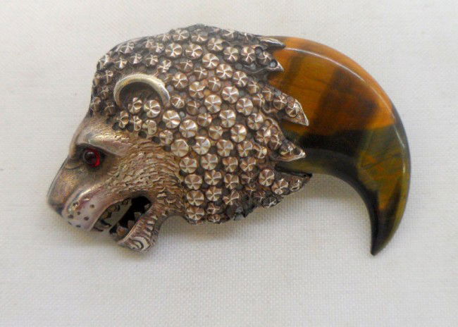 Silver Tigers Eye & Ruby Lion Brooch: Lovely silver tigers eye & ruby eye studded lion brooch. This brooch features a sharks tooth style hand carved tigers eye, as well as a genuine red ruby acting as a studded eye. Please call for shippi
