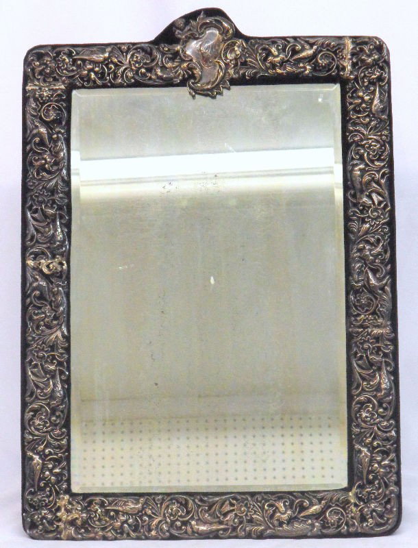Antique Sterling Silver Overlaid Framed Mirror: Antique Sterling Silver overlaid framed mirror. The sterling overlaid sterling is marked, Sterling, on the lower right. Measures 17-1/4" by 12-1/4". Mirror can hang on the wall or for display like a p