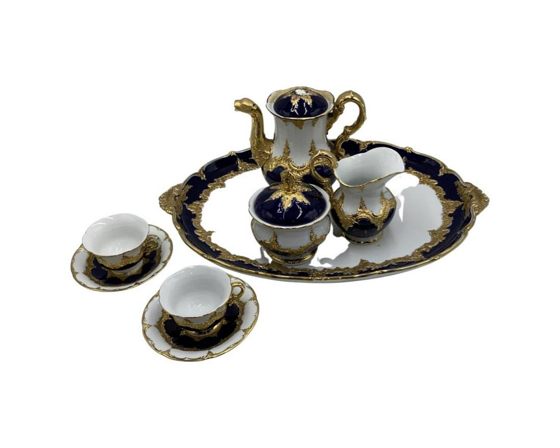 Meissen Porcelain 8pc Demitasse Chocolate Service Set: An 8 piece Meissen German porcelain demitasse / chocolate set having a heavily gold encrusted design with white and cobalt blue glazed grounds. Set is to include a chocolate pot (6 1/2"), creamer (4 1