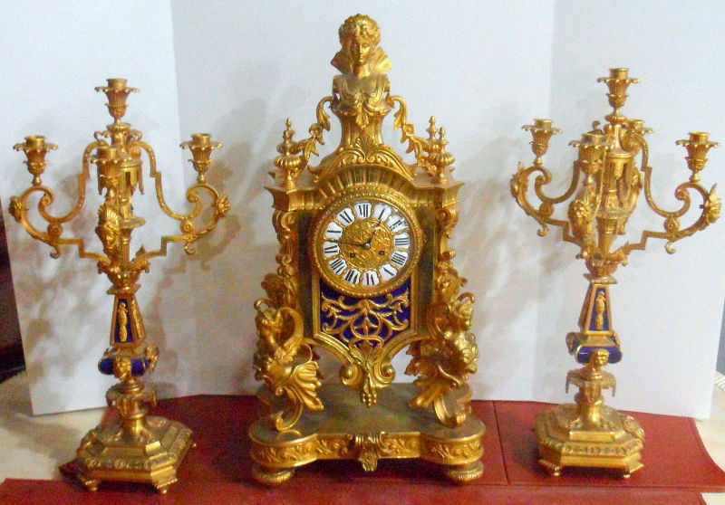 Antique French Sevres & Bronze 3 Pc. Clock Set: Antique French Dore Bronze 3 Piece Clock Set compromising clock with winged goddess on each side with matching candlabras. This magnificent bronze boudoir clock set would make a magnificent statement