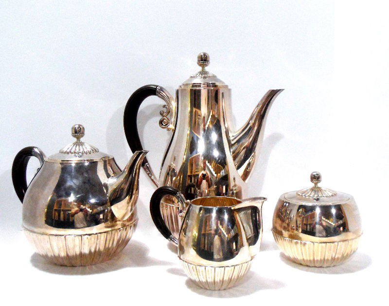 Miyata Japanese Sterling Silver Four-Piece Tea Set: A sterling four piece Japanese sterling silver Miyata tea set. The set is comprised of a tea pot, coffee pot, creamer and sugar bowl. The coffee pot, tea pot, and creamer have elegant dark wooden hand