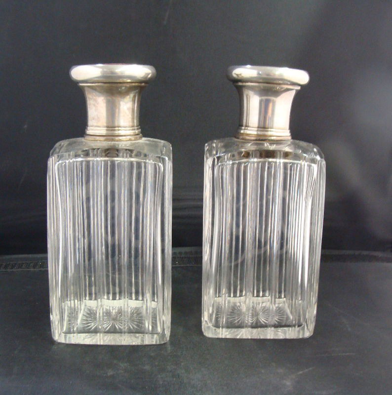 Pair Sterling Enamel and Glass Jars: Pair of glass jars with silver and ruby red enamel tops. Glass has a vertical design with glass stoppers and an enamel and silver top. Silver is hallmarked. Mark is worn (shown in picture). Very good