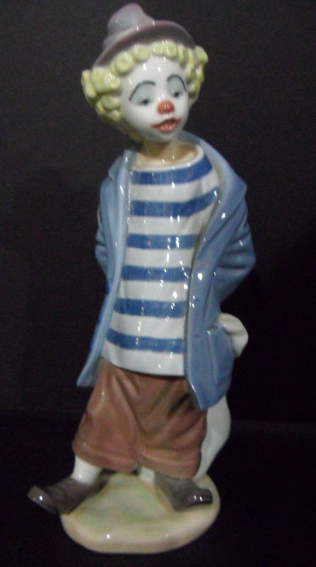 Lladro Porcelain Figure "Little Traveler": Lladro figurine of "The Traveler." The piece depicts a young boy dressed as a clown, and he is carrying a rucksack. Lno.: 7602. Last retail price: $95. Issued 1986-1987. The Lladro stamp along with a 