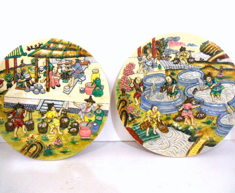 Chinese Porcelain Plaques (2): Pair of Chinese porcelain plaques. Each plaque portrays a different phase in the making of porcelain. One plaque shows men raking pools to gather clay; the other plaque displays men sitting and making