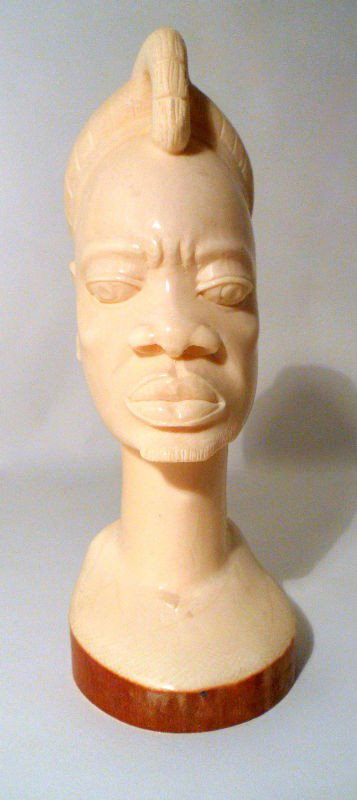 Fine Hand-Carved African Ivory Head of a Man: Fine, hand-carved African ivory carving of a man with a serene countenance. The piece is masterfully carved and features an elaborate hairpiece. 8 1/2"H. Shipping within the continental US is $50 plus