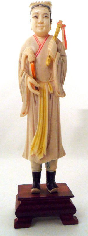 Chinese Carved Ivory and Polychrome Man: Chinese carved ivory and polychrome figure of a man. The man wears robes, which are lined with red and contain a bright yellow sash. He carries objects in each of his hands, which are both painted bri