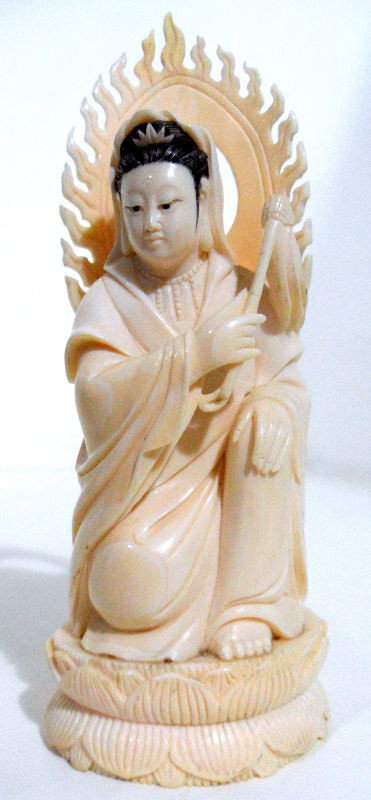 Chinese Ivory Carved Deity: Chinese ivory carved figure of a Buddhist deity. A carved flame sits behind the figure, and a lotus blossom serves as the base. The figure holds a swatter and wears heavy robes. Measures 6 3/4"H. Ship