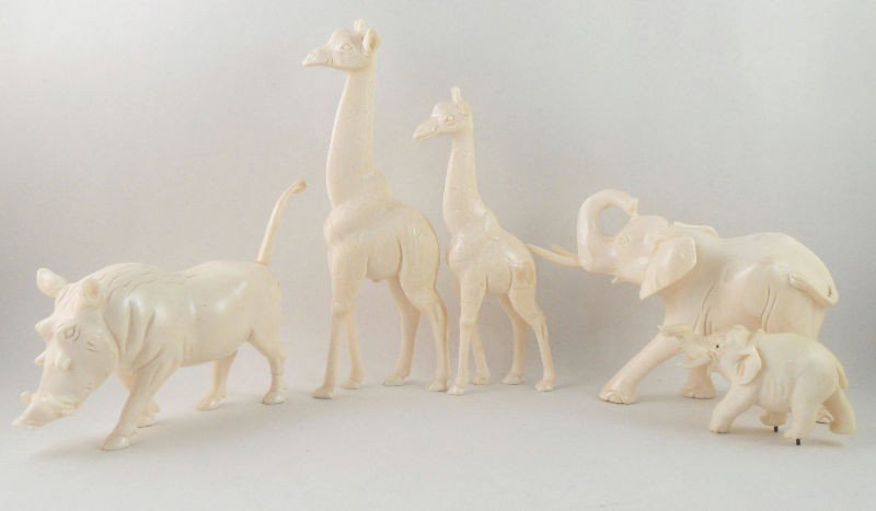 African Carved Ivory Animal Figures (5): African ivory carved figures of animals. The animals depicted include 2 giraffes, 1 warthog, and 2 elephants. Each animal is delicately carved to lifelike quality. Measurements vary from 1 1/2"H to 5"