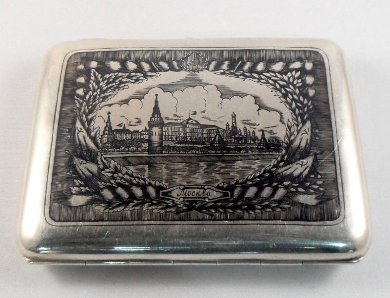 Russian Silver Case with Cityscape Design: Russian silver case with an image of a city entitled Mockba on the front. A clasp with a purple stone is visible on the side. The case opens up an reveals an interior gold wash. Kokoshnik marks and a 