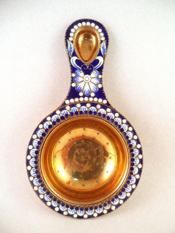 Russian Sterling Silver and Enamel Tea Strainer: Russian sterling silver and enamel tea strainer. The outer rim of the pieces is beautifully decorated with a blue and white floral enamel design. A gold wash covers the entire piece. Russian hallmarks