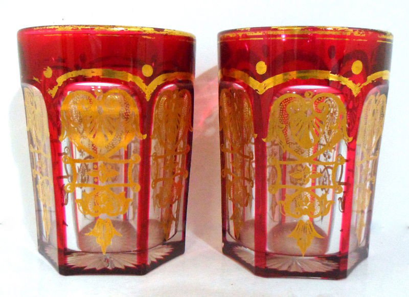 Bohemian Red and Gilt Glasses (7): Set of 7 Bohemian red and gilt glasses. Each red glass is beautifully cut with clear panels containing an elaborate gilt design. The rim and top section of each glass exhibits some loss of gilt design